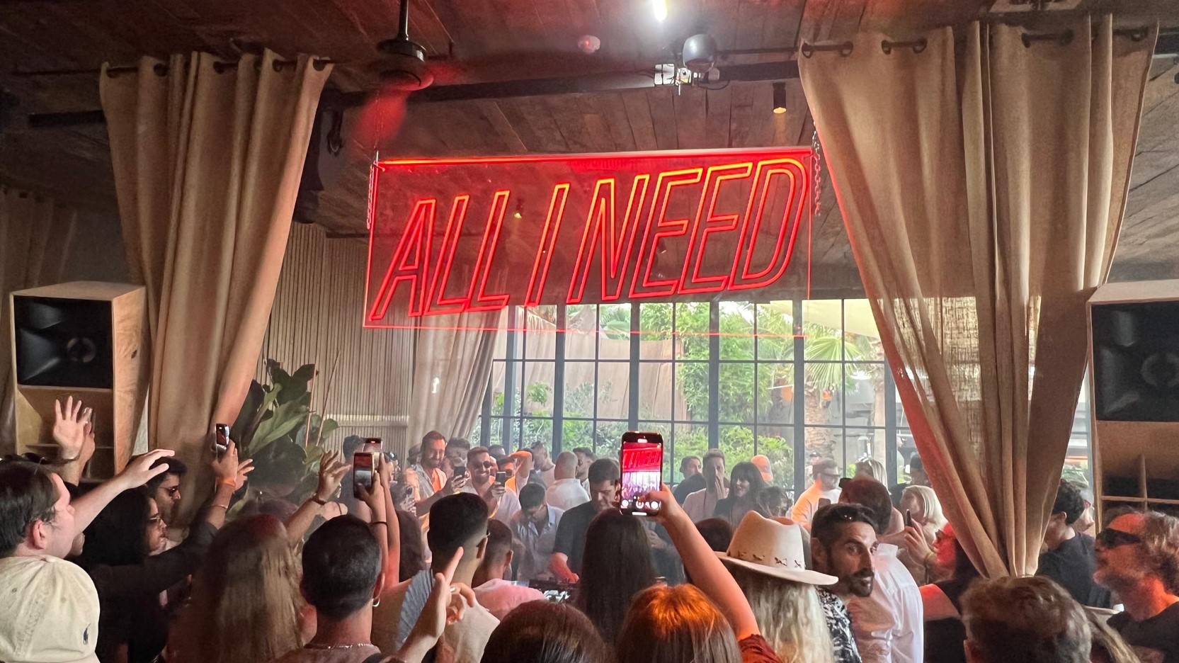 ALL I NEED Neon-Schild ueber tanzender Menge mit erhobenen Haenden